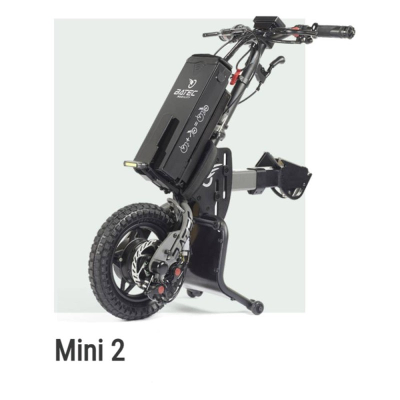 Handbike BATEC MINI 2 de color gris grafito plegado y anclado a una silla de ruedas manual, destacando su motor eléctrico.