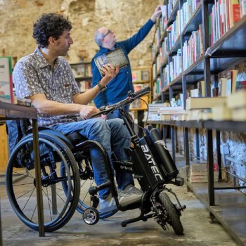 Handbike BATEC AIR de color negro acoplado a una silla de ruedas manual, destacando su diseño ultra compacto.