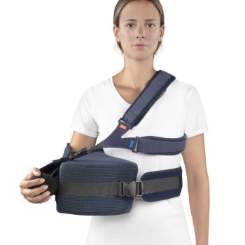 Cabestrillo ortopédico de rotación externa posicionado a 90 grados con soporte de antebrazo y pelota de rehabilitación.